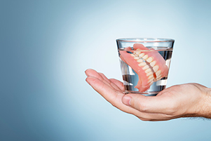 A set of dentures in a glass of water at Stephen L Ruchlin DDS in Rochester, NY