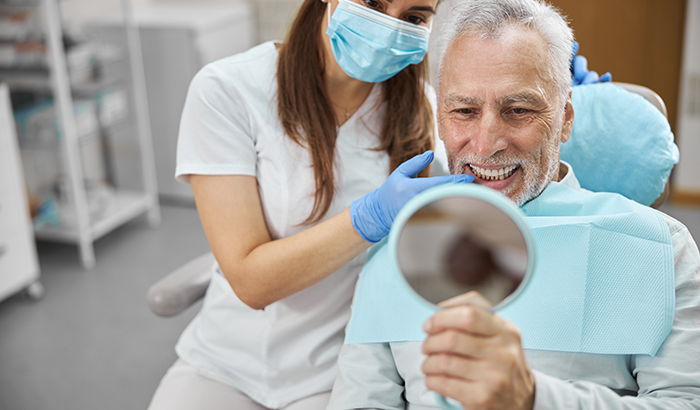 a patient looking in the mirror smiling after dental implant placement a patient looking in the mirror smiling after dental implant placement