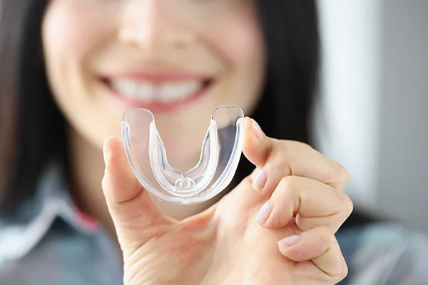 Close up of a simple mouthguard being held up by an excited white woman