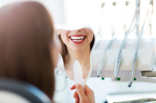 Woman looking at her smile in a mirror Woman looking at her smile in a mirror