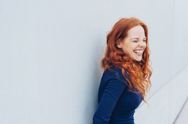 Woman leaning against wall after smile makeover at Stephen L Ruchlin DDS.